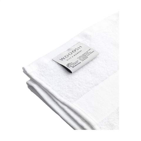 This sustainable towel from the Wooosh Brand is made from 50% recycled cotton and 50% cotton. The towel has a handy loop and a woven band and is beautifully finished with a cotton trim. The softness of the tightly woven terry gives a feeling of luxury and comfort after an invigorating shower or warm bath. The fibres of the 400 grams of terry cotton are highly moisture-absorbent and feel pleasant on your skin while drying. This bathroom textile has a timeless look and fits into any interior. This product is GRS-certified and produced with special attention paid to people and the environment.